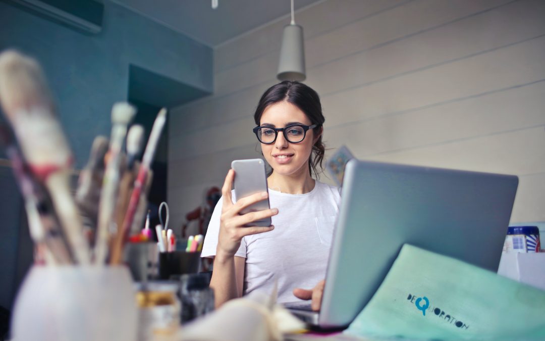 SmallBusiness woman looking at phone and sitting at their desk.