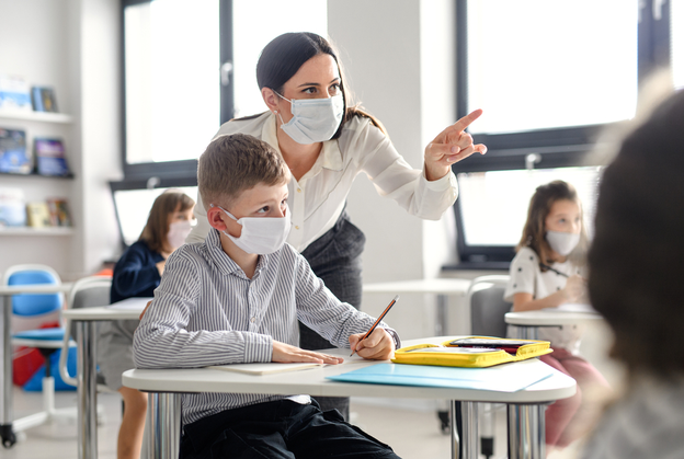Teacher with young students in the classroom wearing masks