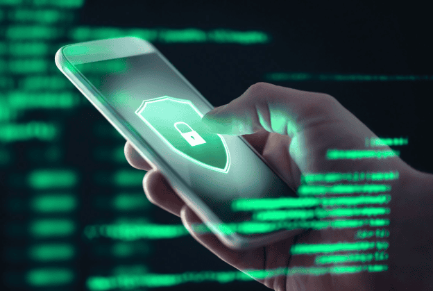 A hand holding a smartphone with a glowing security shield icon on the screen, surrounded by green digital code, symbolizing mobile cybersecurity.